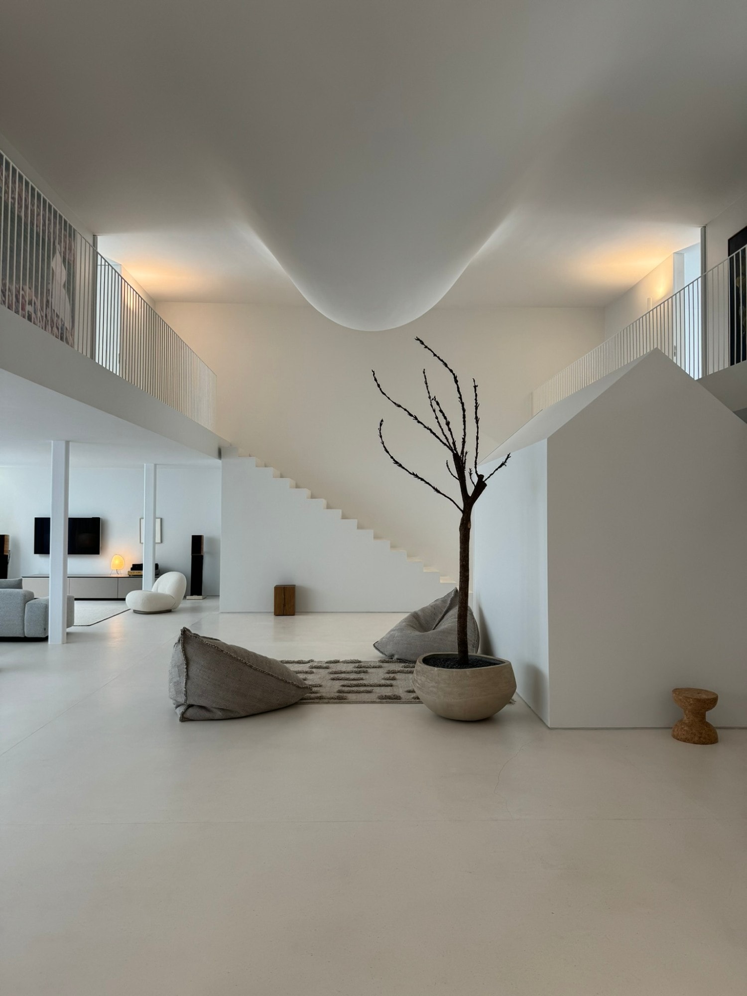 Interior de doble altura con escalera, un árbol en maceta y luz cálida — fotografía de arquitectura de Espacio Bacán