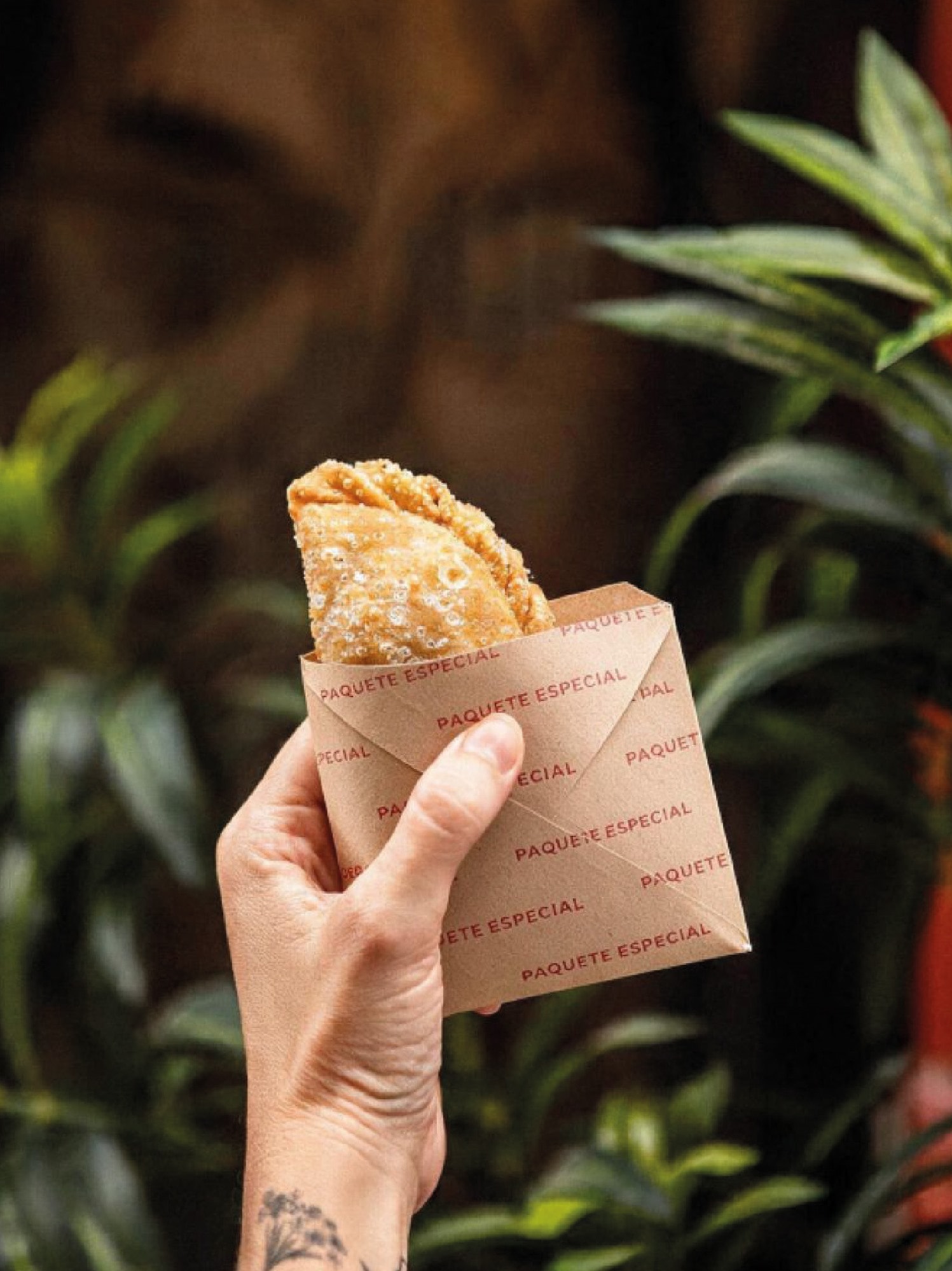 Empanada en mano con el papel de Estación Cero
