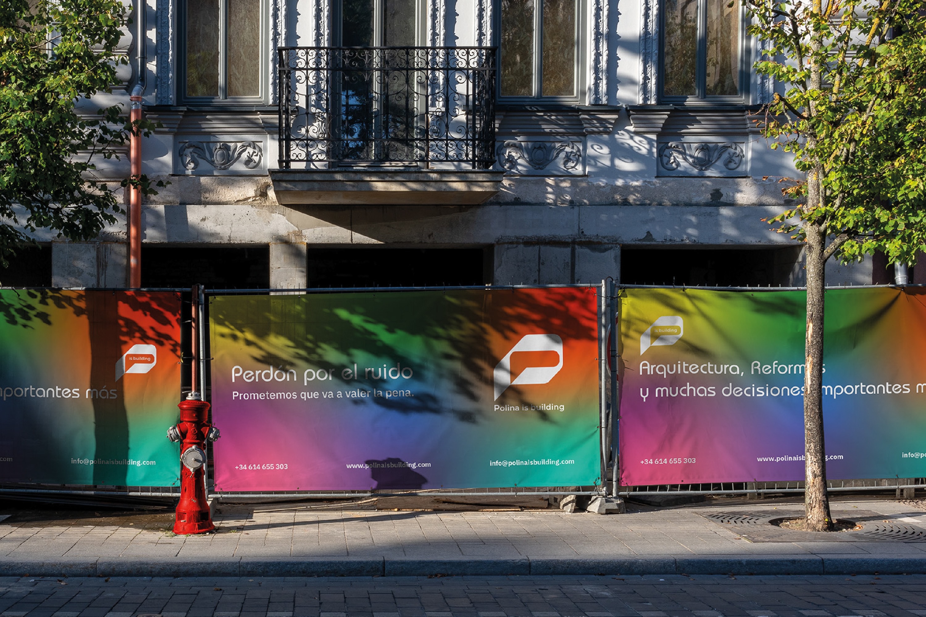 Lona de obra con la identidad de Polina is Building sobre la fachada de un edificio