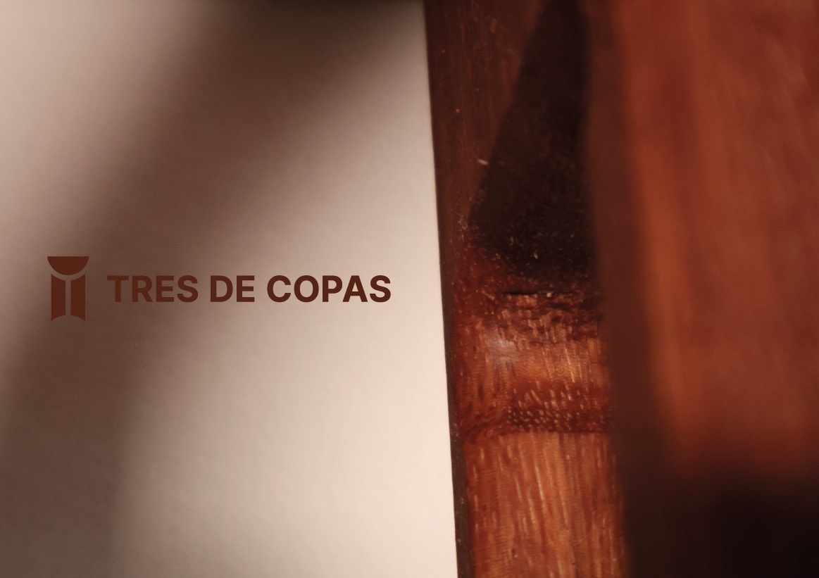 Logotipo de Tres de Copas sobre madera y luz cálida